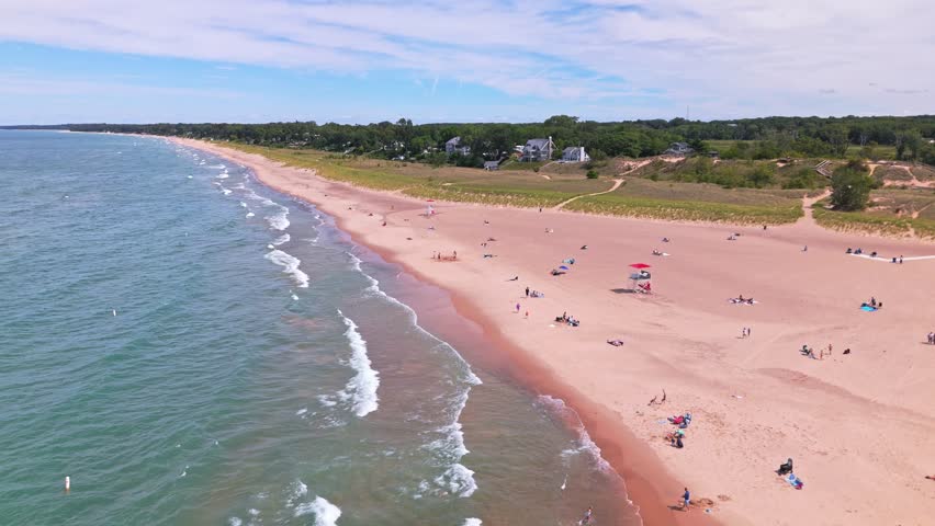 Low aerial flyover of New Buffalo Beach, Michigan, with stunning views over Lake Michigan and the peaceful shoreline on a sunny summer day