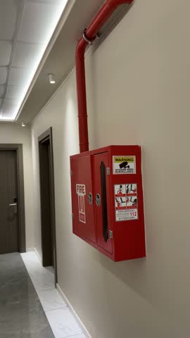 Fire extinguisher cabinet on wall in hallway safety equipment with warning signs background video