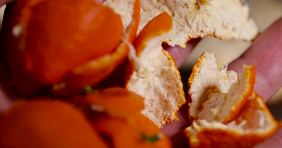 peel of peeled oranges in the hand, a large amount of peel of peeled citrus fruits on the table, close up