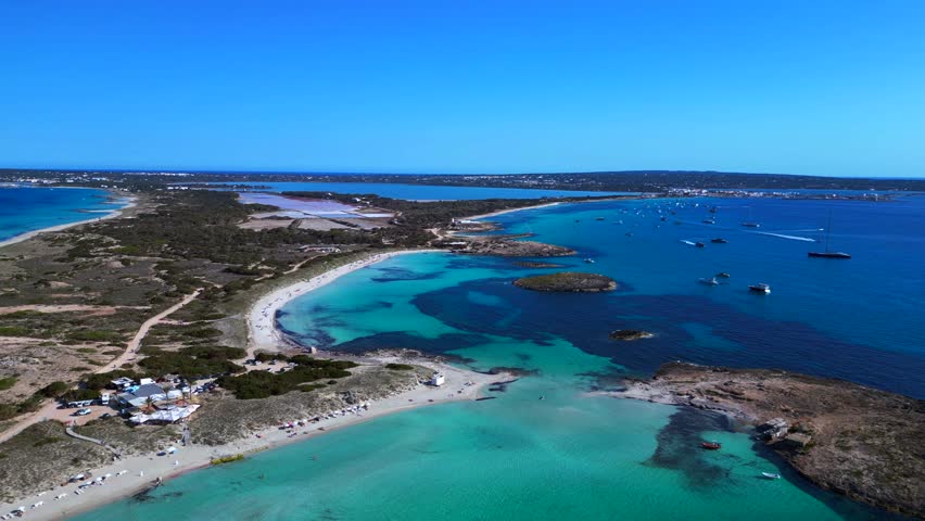Formentera island landscape Ses Illetes beach bay with shallow blue turquoise sea and boats. Stunning aerial view rotation pan to left panorama overview drone