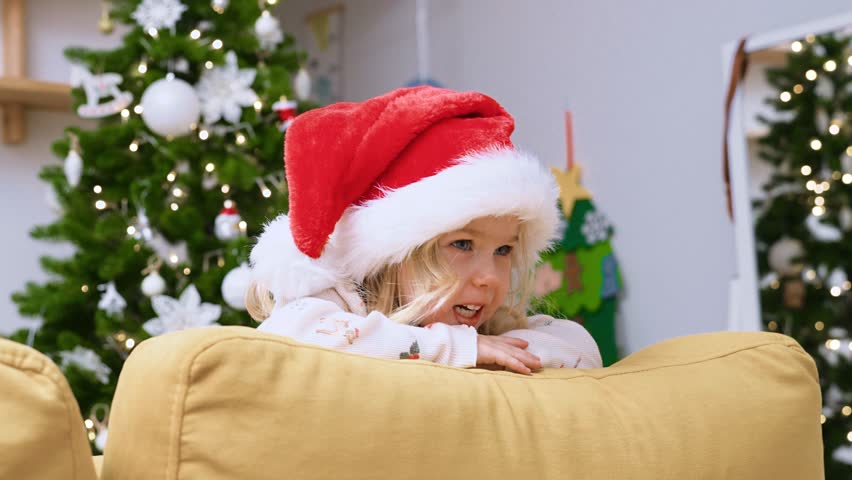 Home portrait of a child girl in a Santa hat. The concept of New Year