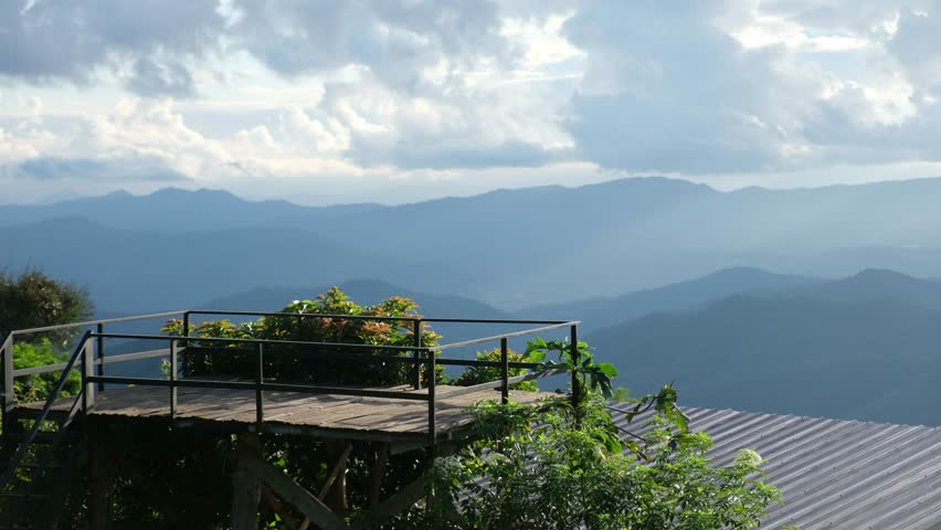 Landscape image of mountain views and cloudy sky from wooden terrace viewpoint