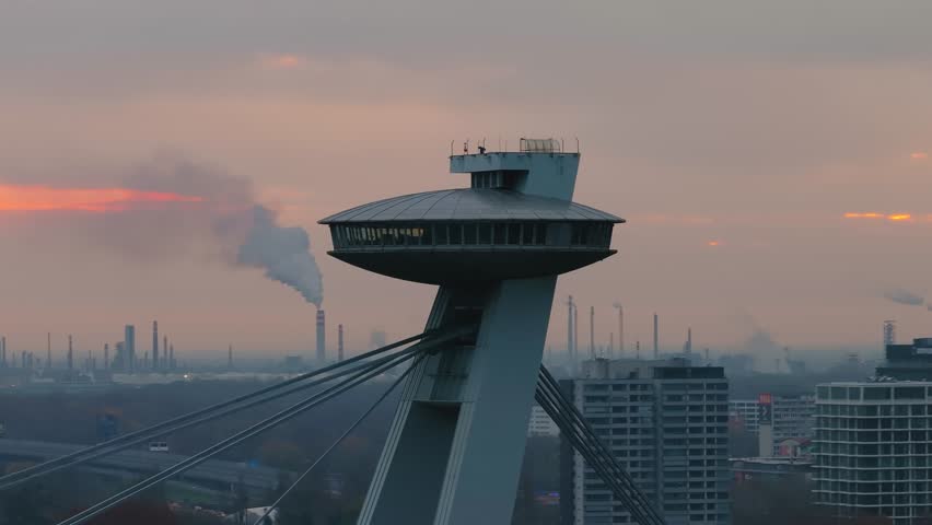 4K cinematic drone footage of the UFO Tower in Bratislava, showing the futuristic observation deck rising above the SNP Bridge with sweeping views of the Danube River _16