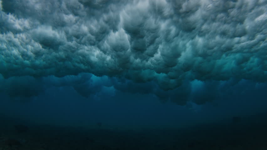 Underwater view of the ocean wave breaking on the shore during sunset light in the Maldives