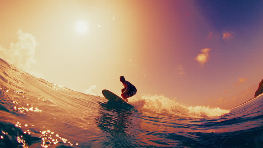 Surfer rides the ocean wave in the Maldives during sunset