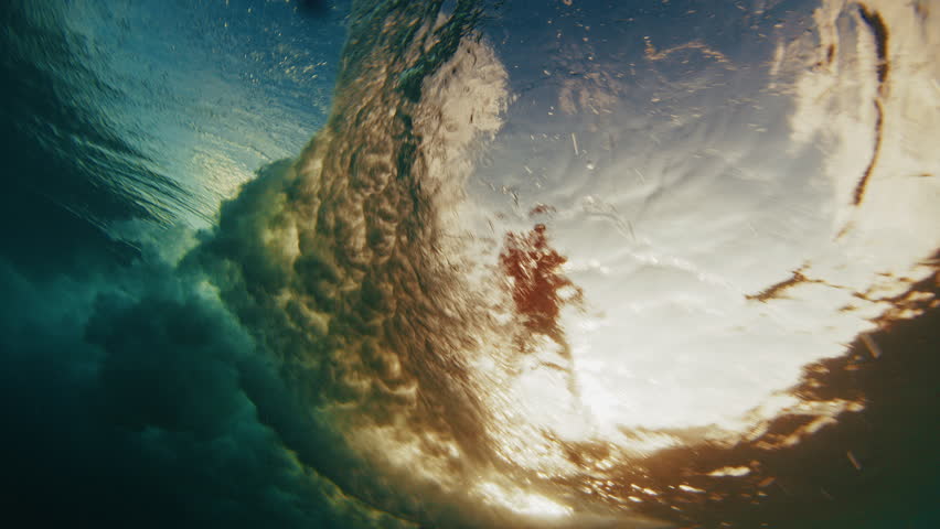 Underwater view of the ocean wave breaking on the shore during sunset light in the Maldives