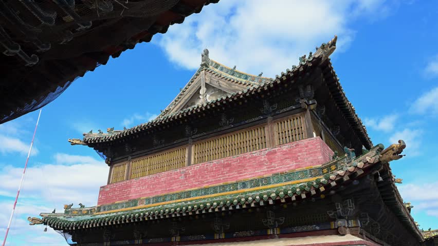 Scenic exterior of the historic temples at Erdene Zuu. The 16th-century structures display ornate green eaves against the sky, preserving the ancient religious artistry of Karakorum.