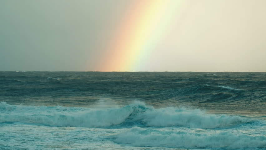 Hawaiian seascape. Waves break on the Hawaiian shore with rainbow on the background on the Oahu island
