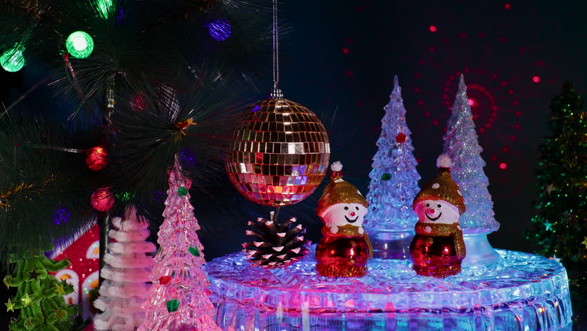 Snowmen, Christmas trees and a pine cone near a hanging checkered Christmas ball on a decorated Christmas tree