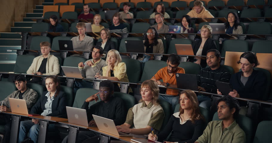 Diverse University Students Sit in Lecture Hall, Typing on Laptops, Jotting Notes, and Concentrating on an In-depth Higher Education Lesson, Research Concepts, and Collaborative Academic Learning.