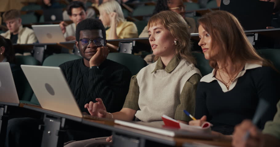 University Classmates Sit Together in Lecture Hall, Working on Laptops and Taking Notes as They Review Course Material, Clarify Concepts, on Academic Success and Understanding.