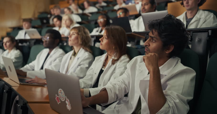 Medical Students in White Lab Coats Lesten to University Lecture, Typing on Laptops as They Build Knowledge for Careers in Surgery, Cardiology, Radiology, Emergency Medicine, Oncology, Primary Care