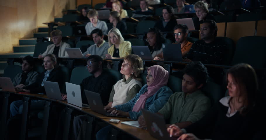 University Lecture Theater, Students Work on Laptops and Write Notes, Following an In‑depth Academic Presentation, Listening Carefully and Engages With the Challenging Course Material. Modern Education