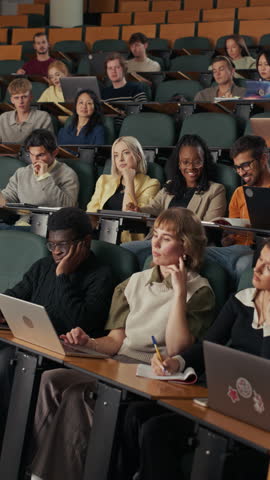 Vertical Lecture Hall Video of Diverse University Students Listening, Typing on Laptops, Raising Hands, Critical Thinking, Academic Dialogue, Interactive Higher Education, Webinar, E-learning.