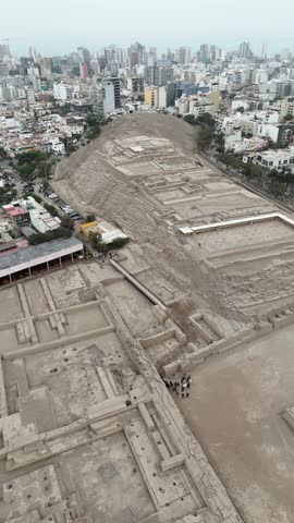 View of Huaca Pucllana pyramid ruins in the middle of a modern cityscape. Lima, Peru. Aerial vertical video.