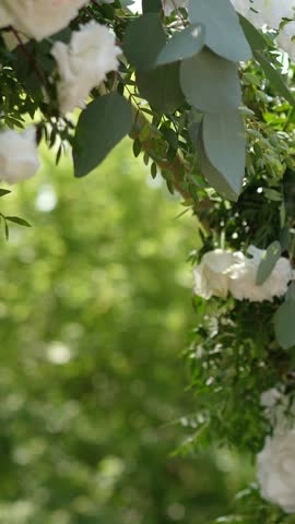 wedding arch of white rose flowers on the nature before the wedding ceremony of the bride and groom, festive romantic decor