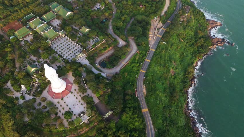 Scenic aerial view of a winding coastal road on Son Tra Peninsula at sunset. Beautiful travel route near Lady Buddha statue in Da Nang, Vietnam