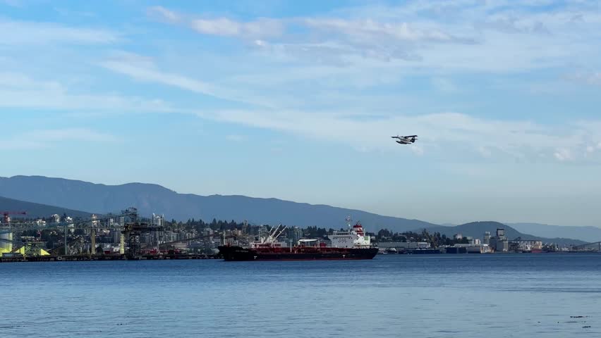 Handheld wide tracking shot of a seaplane flying over Vancouver Harbour past Lions Gate Bridge on a fall day in British Columbia, Canada. 4K