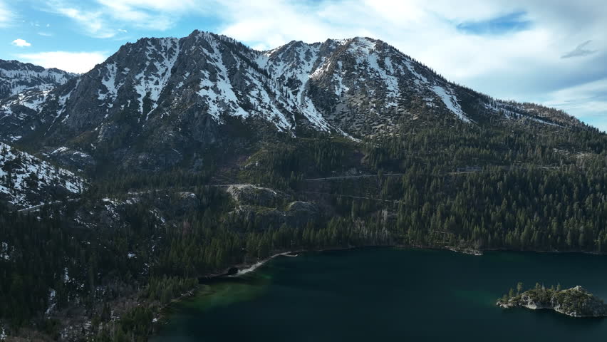Aerial view approaching snowy mountains of lake Tahoe, cloudy, winter day in USA