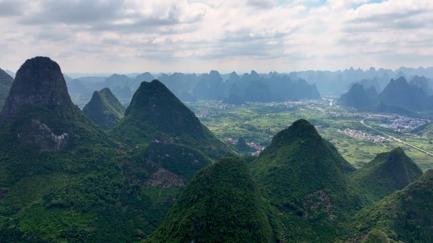 Aerial Drone Views of China Dramatic Mountain Shapes. Bright Green Slopes and Quiet Settlements. Revealing Timeless Beauty and Grand Scale of Beautiful Asian Landscape. Vacation Travel Destination 4k