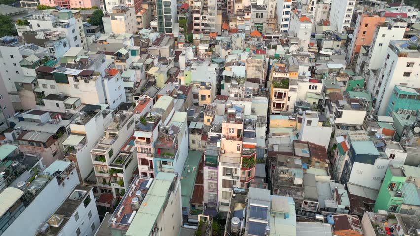 Drone aerial view of dense residential housing and rooftops in Ho Chi Minh City, Vietnam. Compact urban landscape showing everyday city life, architecture, and crowded neighborhoods in Southeast Asia.