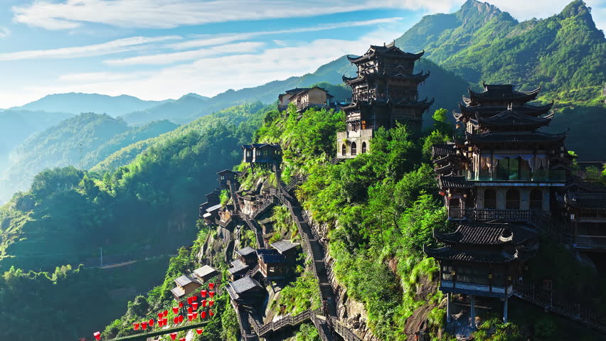 Aerial shot of traditional chinese wooden pavilions and cliffside houses on green mountain. The famous Wangxiang Valley Scenic Area is located in Jiangxi, China.