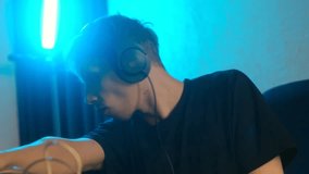 Young focused male music producer with headphones working on a sound mixer, creating electronic music in a professional studio with blue neon light, composing and arranging a new audio track - Powered by Shutterstock - Get 15% off with code: PIKWIZARD15