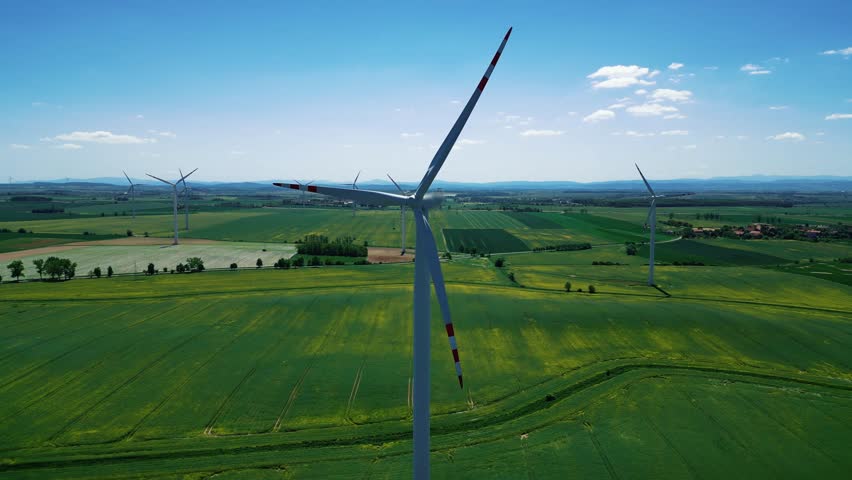 Blades of the wind generator rotate, generating clean energy. Wind farm generating renewable energy, rural green landscape. 4k footage