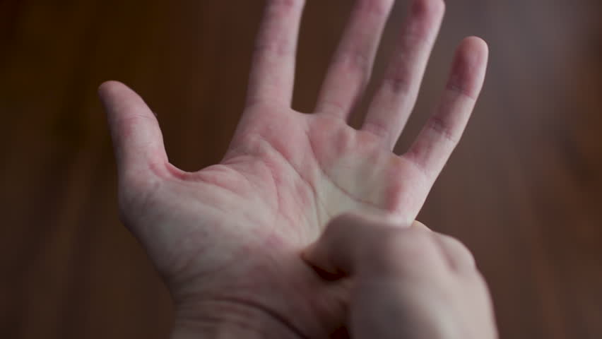 Close-up view of a man's hands performing a therapeutic self-massage on the palm and fingers to alleviate joint pain and tension