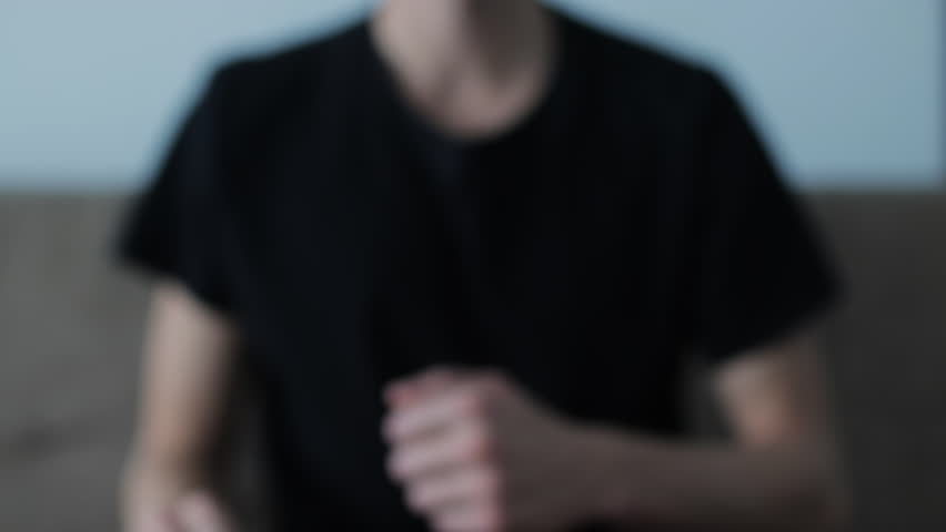 Close-up of a male hand showing a thumbs-up gesture. The young man in a black shirt expresses approval, success, and positivity
