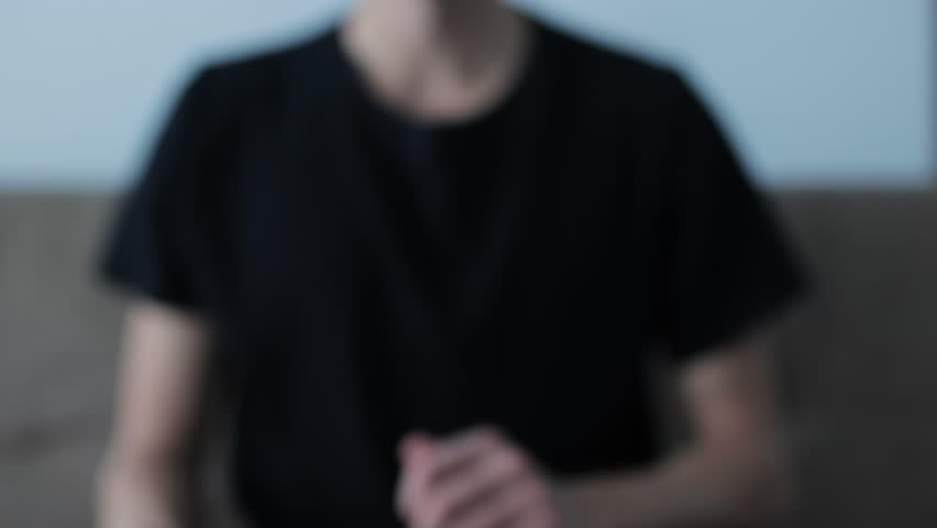 Close-up of a hand gesturing to stop, with a blurred figure in the background indicating denial, rejection, and disagreement