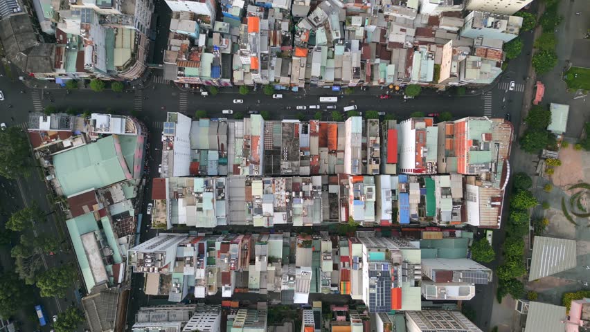 Top-down aerial view of dense urban housing and narrow streets with city traffic in Ho Chi Minh City, Vietnam. Compact architecture, everyday urban life, and growing Asian metropolis.