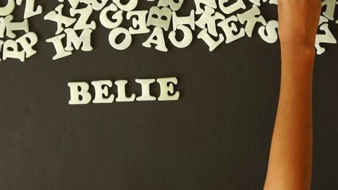 A person spelling Believe in yourself with plastic letters