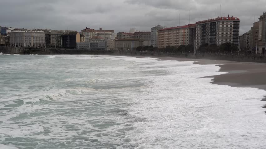 Cloudy beach and distant city buildings create a contrast between nature and urban landscape