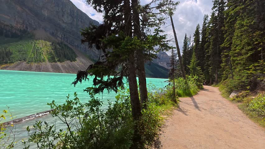 Turquoise water of lake louise invites hikers to explore the scenic lakeside trail, surrounded by majestic mountains and lush greenery in banff national park, alberta, canada