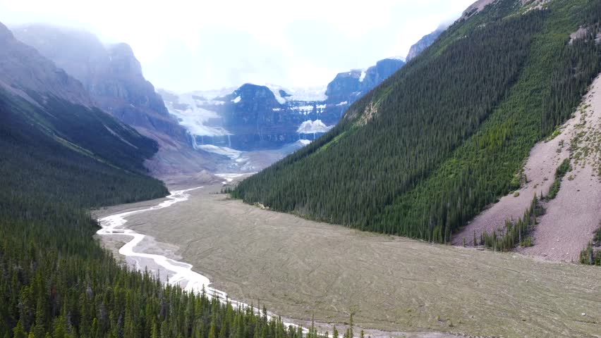 Sunwapta river is flowing from the athabasca glacier, part of the columbia icefield, surrounded by lush forests and mountains in jasper national park, alberta, canada