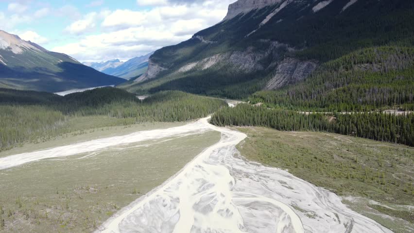 Sunwapta river meandering through lush valley, framed by majestic mountains near columbia icefield, revealing turquoise glacial waters contrasting with green landscape in canadian rockies