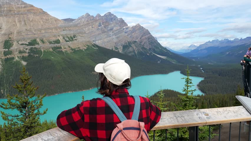 Majestic peyto lake, nestled amidst the canadian rockies in banff national park, captivates a tourist gazing at its turquoise expanse and surrounding mountains