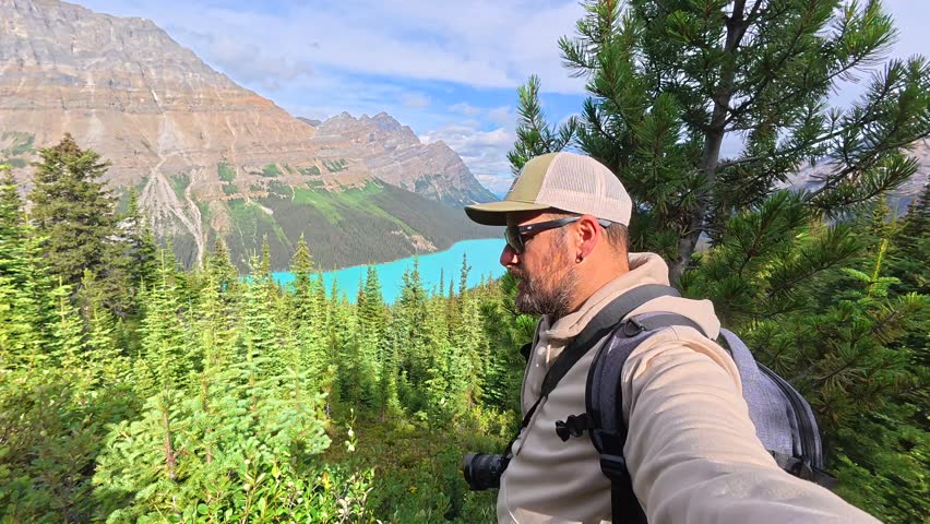Breathtaking views of the turquoise peyto lake and surrounding canadian rockies unfold as a photographer hikes through lush pine forests in banff national park, capturing the stunning scenery
