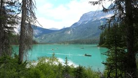 Emerald lake, nestled in the canadian rockies, hosts tourists canoeing across its turquoise waters, surrounded by lush forests and majestic mountains under a summer sky - Powered by Shutterstock - Get 15% off with code: PIKWIZARD15