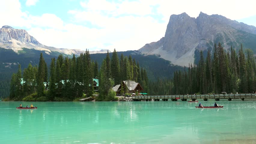 Emerald lake lodge nestled on small island, surrounded by pine trees and mount burgess, with kayakers exploring turquoise waters of scenic canadian landscape