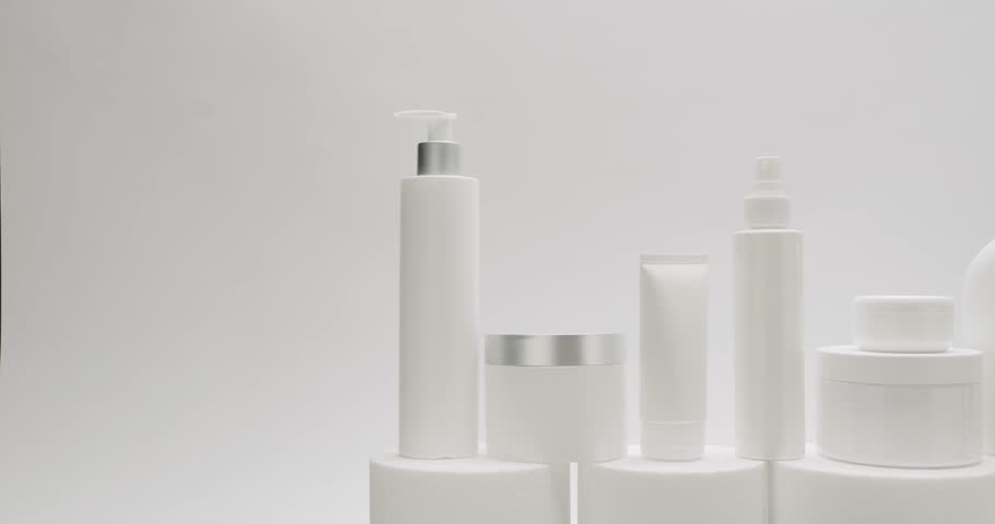 White Bottle and tubes for cosmetics on a white background in studio. Natural cosmetics production for hair and skin care. Glossy cosmetic jar with cream. Group of different cosmetic bottles.