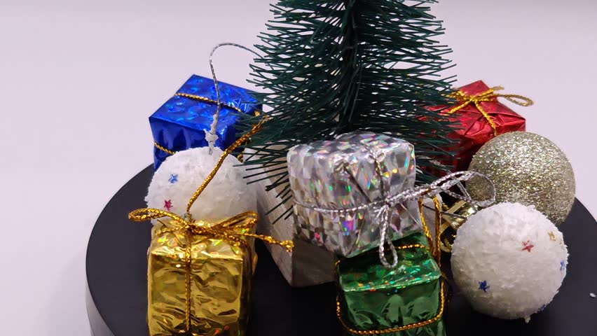 Christmas tree with toys, gifts, and lights. Festive atmosphere, circular motion, light background.