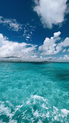 clear turquoise water and gentle waves extend toward the horizon beneath a bright sky during a peaceful ferry journey near cancun.