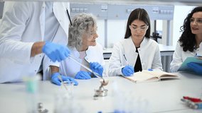 Senior male teacher explaining a chemical reaction with fire to a group of female students during a practical lesson in a science lab - Powered by Shutterstock - Get 15% off with code: PIKWIZARD15