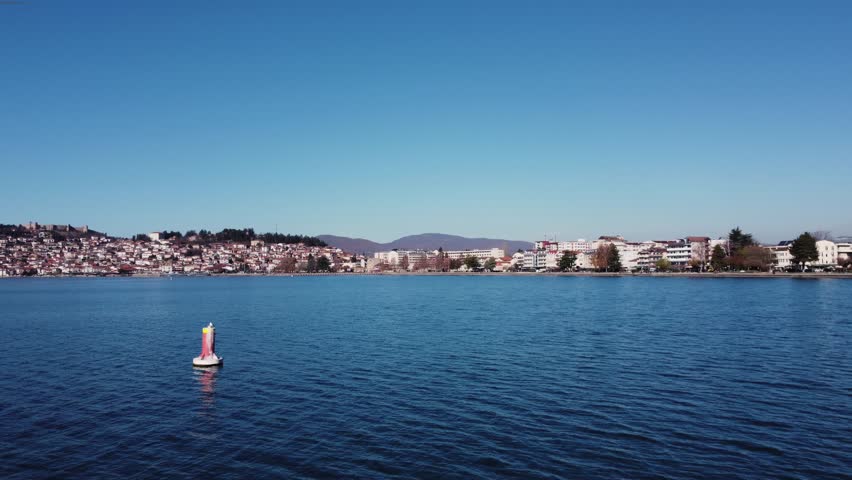 Scenic view of Lake Ohrid with a seagull perched on a buoy and the city of Ohrid in the background.