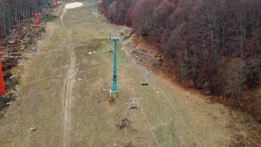 Chairlift on ski slope. Empty ski lift on a grassy mountain in autumn. A ski lift going uphill.