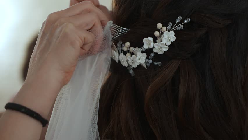 Bride Adjusting Floral Hair Comb With Hands, Pearl And Crystal Comb Pinned Into Dark Waves, Veil Being Set In Place By Stylist, Intimate