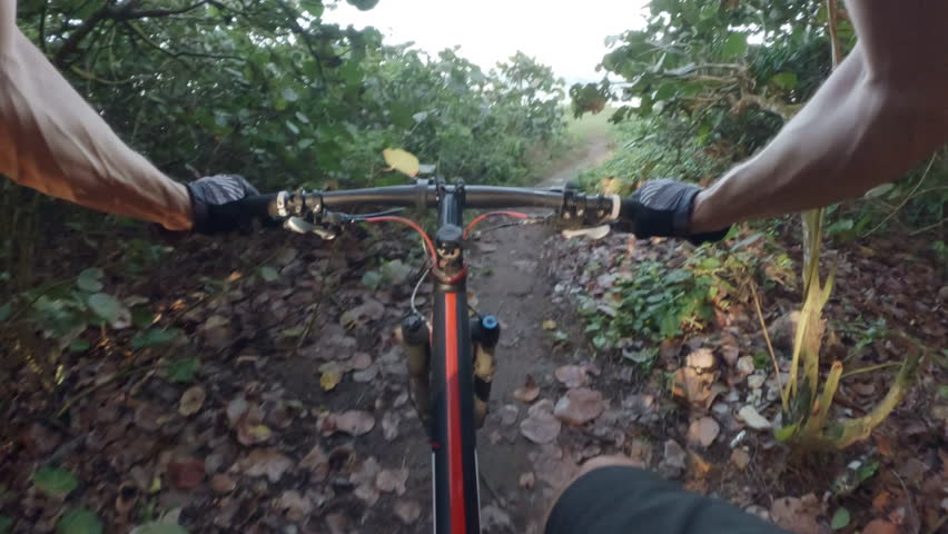 POV. Cyclist rides a mountain bike next to ocean.
