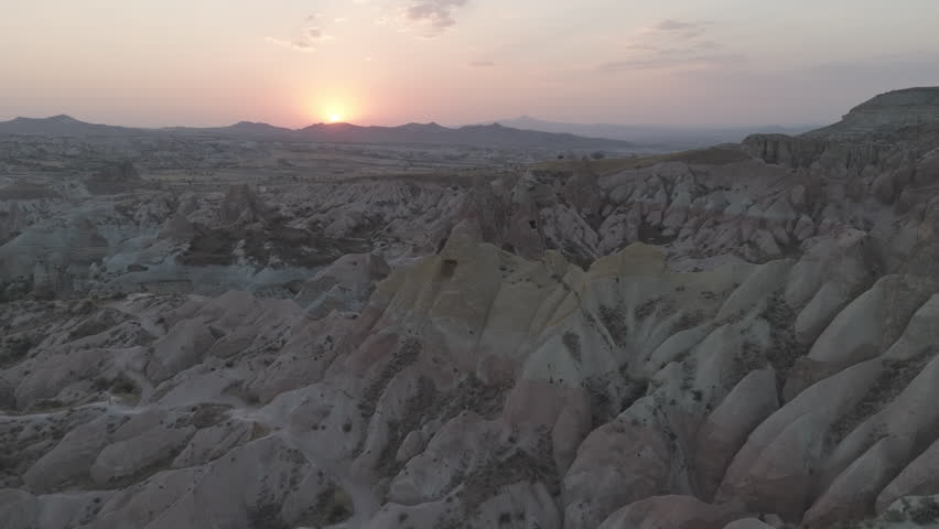 D-Log M. Goreme, Nevsehir, Turkey. Aerial view of multicolored rock layers in Red Valley at sunset, showing red, orange and yellow hues. Aerial View, Departure of the camera, MasterShots